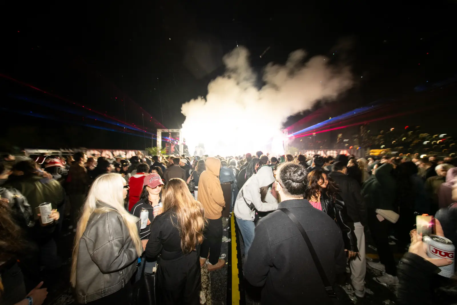 An outdoor crowd in front of a smoke-filled stage