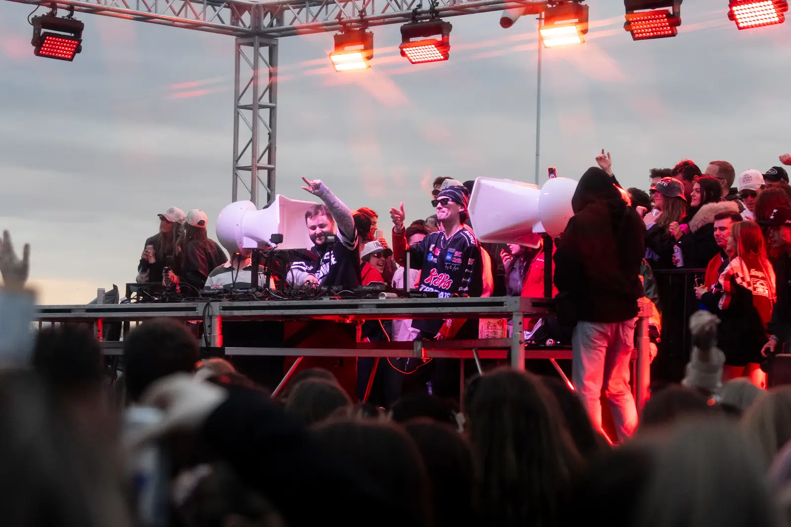 An outdoor stage at dusk, the crowd pressed up to it